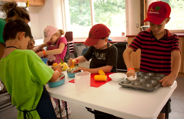 Children preparing muffin tins and zucchini for chocolate chip zucchini muffins.